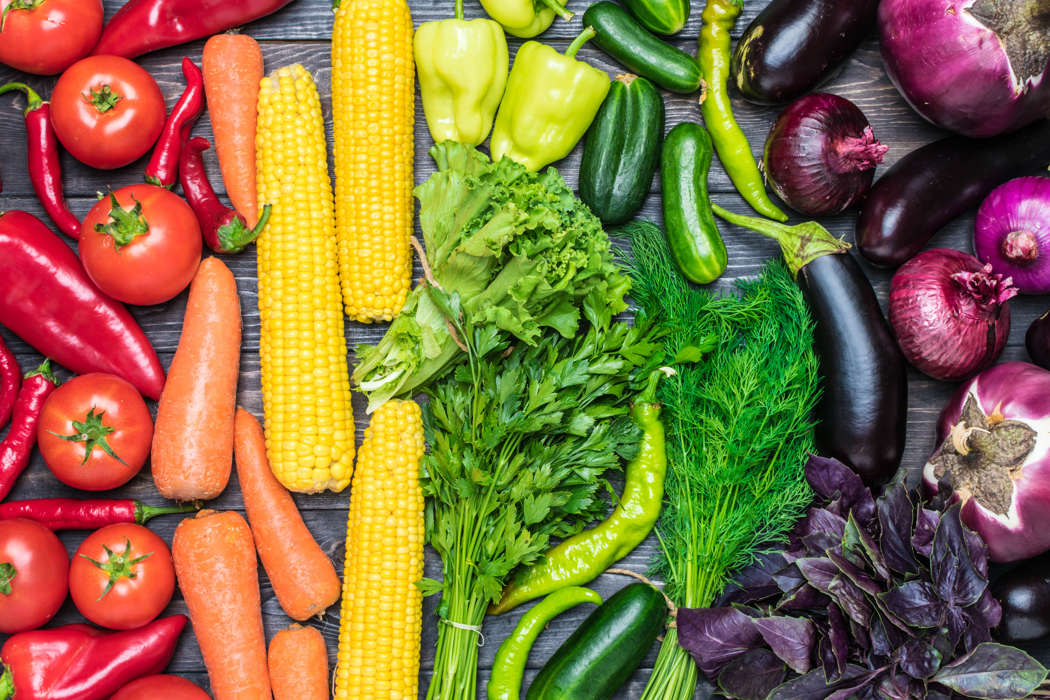 Primex Garden Center-Glenside-Pennsylvania tabletop arrangement of a variety of fresh fruits and vegetables sorted by colors - pepper, tomato, corn, carrot, green salad, cilantro, eggplant, cucumber, basil, dill, onion. Healthy food concept